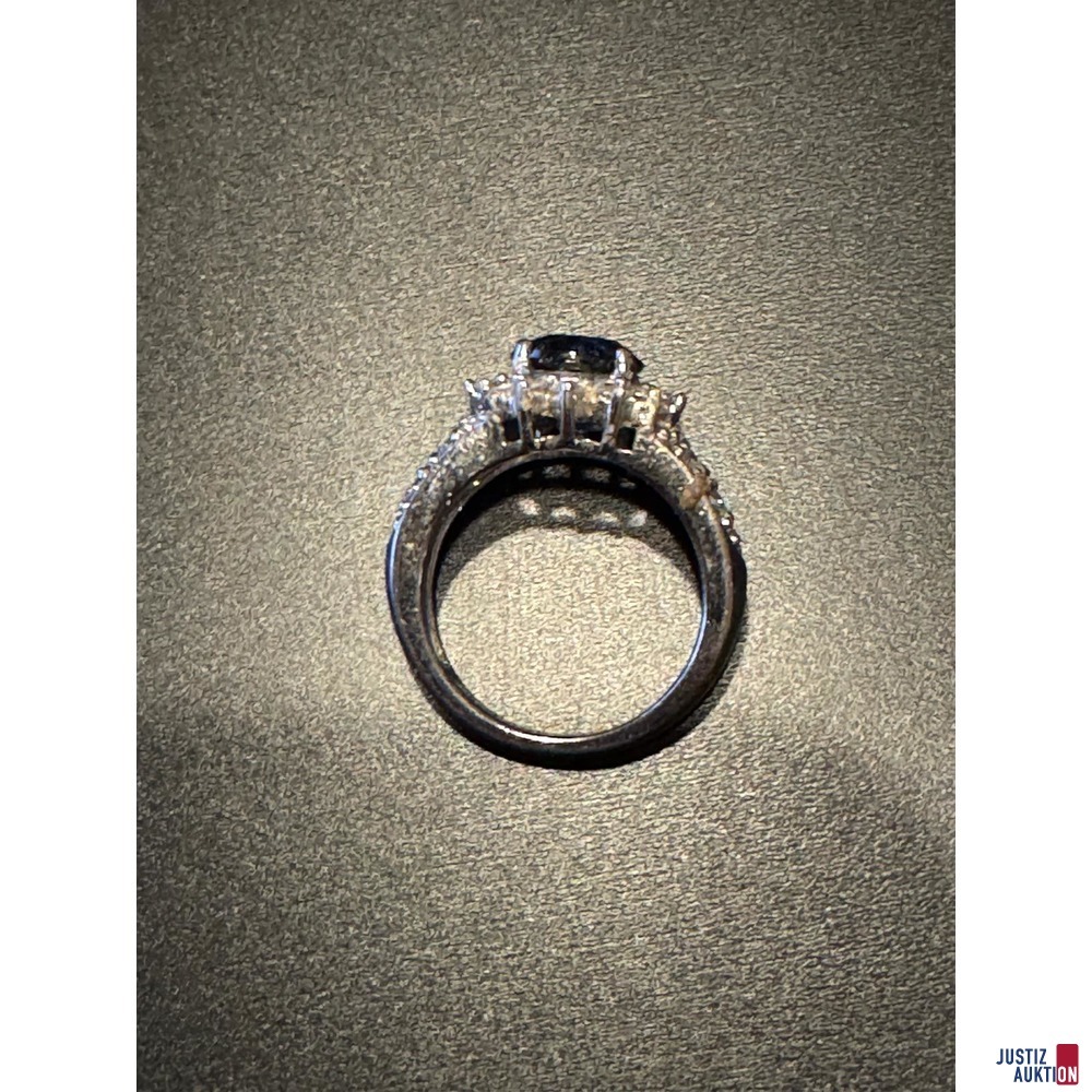 Silberfarbener Ring mit kleinen wei&szlig;en und gro&szlig;em blauen Stein