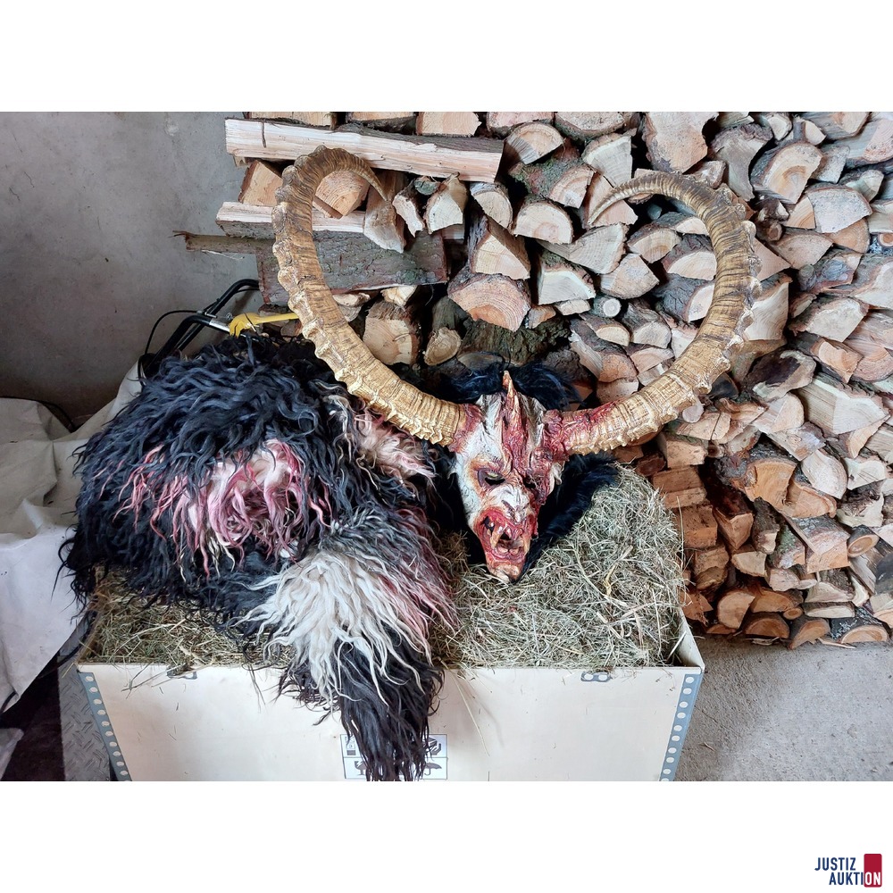 2 Perchtenmasken mit einem schwarzen Fell und Stock mit Geisfuß